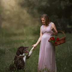 A charming and playful outdoor scene where an expecting mother and her dog share a "handshake." It’s a lighthearted moment that perfectly captures their sweet bond.