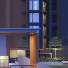 A close-up of an architectural corner at night, where uplighting on a textured pillar and the warm glow from windows create a composition of light, shadow, and material.