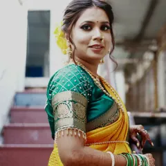 A beautiful Maharashtrian bride. Her look features a subtle yet glowing makeup, a traditional nose ring (nath), and a simple but elegant hairstyle adorned with yellow flowers.