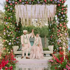 The happy couple celebrates at their pastel floral mandap, set on a stunning mirrored aisle that reflects the sky and the beautiful decor.