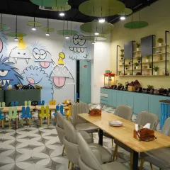 A look at our spacious and colorful dining area, featuring fun monster murals on the wall. We have a mix of kid-sized tables and comfortable seating for adults.