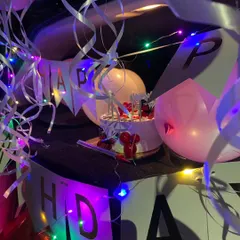 This shot focuses on the details of the car trunk decor, with swirling ribbons, a birthday cake, and a banner illuminated by multi-colored fairy lights for a festive feel.