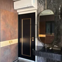 This image shows how we design around existing architectural elements, like doors and air conditioning units, to create a fully integrated look. The wardrobe, door, and vanity all share a cohesive design language with matching gold accents.