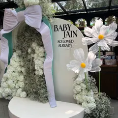 For this dreamy baby shower, we created a bespoke backdrop featuring a giant fabric bow, clouds of baby's breath, and oversized whimsical daisies. This is our signature modern and chic event styling.