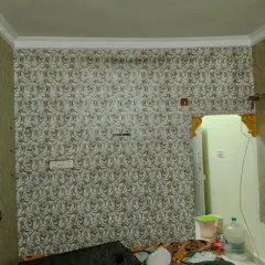 A grey rose-patterned wallpaper installed in a room, with careful cuts around the door frame.