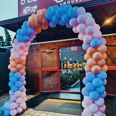 A vibrant balloon arch at the entrance of a restaurant for a private party. The mix of pink, blue, and orange balloons creates a fun and festive atmosphere.