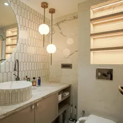 A washroom featuring a mix of marble and textured tiles, a round vessel sink, and elegant globe pendant lights.