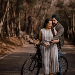 A fun and candid moment with a bicycle on a tree-lined road. This shot from Karan and Simarpreet's pre-wedding session is playful, natural, and full of personality.