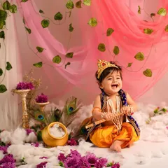 A burst of pure, divine laughter. This little Krishna's joyful expression is the heart of this photo, captured in our vibrant and playful Janmashtami setup.