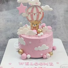 A sweet "Welcome Angel" cake. This pink cake features a teddy bear in a hot air balloon, surrounded by fluffy clouds and stars.