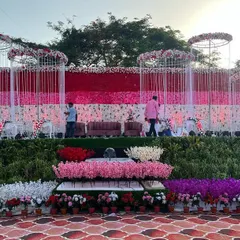 This reception stage features a massive wall of flowers, blending shades of red, pink, and white for a dramatic effect. In front, I created a garden-like setting with rows of colorful blooms.
