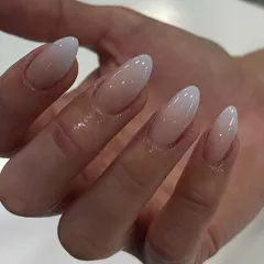 A close-up of a flawless white-to-nude ombré on long almond nails, showcasing the smooth gradient effect.