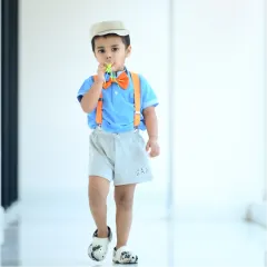 A stylish little boy dressed like Blippi, walking confidently in a bright, open corridor.