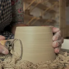 Molded from the earth, shaped by the soul. A close-up of the trimming process, where shavings of clay fly off the spinning pot.