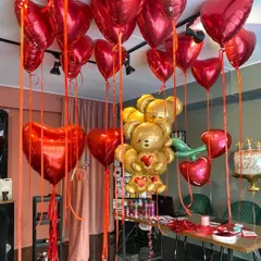 We are ready for Valentine's Day. This room setup is filled with red heart-shaped helium balloons and a giant teddy bear made of gold foil balloons.