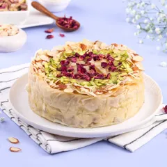 This is my fusion creation, the Baklava Cheesecake. It combines the creamy texture of cheesecake with the crispy, nutty, honey-soaked layers of traditional baklava, garnished with pistachios and rose petals.