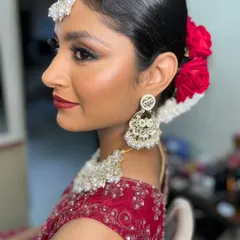 This is for the bride who loves a touch of drama. We went for a glamorous reception look with a sharp winged eyeliner, a bold red lip, and radiant, glowing skin. The sleek hair, adorned with vibrant red roses, pulls the entire look together, making it perfect for an evening of celebration.