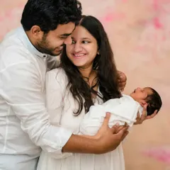 A joyful moment between new parents and their baby. I encourage natural interactions to capture genuine smiles and emotions during newborn family photoshoots.
