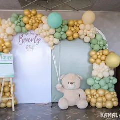 A soft and elegant teddy bear theme using a palette of sage green, beige, and gold. This photo booth setup includes a 'We Can Bearly Wait' sign and interactive boards for guests to guess the baby's gender.