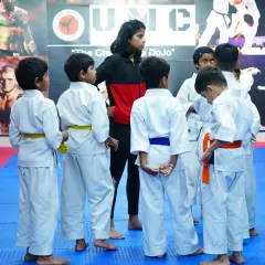 A coach gathers a group of young karate students for instruction. We foster a supportive environment where every child gets personal attention.