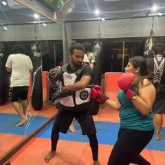 Learning to target the body is key for self-defense. Here, a student practices body shots on my chest guard, a drill that builds power and toughness.