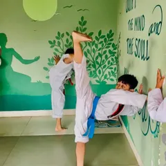 A student performs a wall-assisted side split, an essential stretch for developing the flexibility needed for head-high kicks.