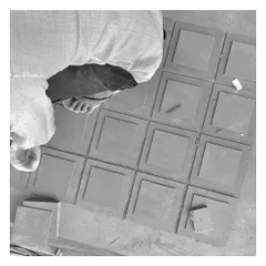 A craftsman carefully lays out custom-cut tiles. This black and white shot captures the hands-on effort and skill that goes into creating the unique details of our projects.