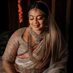A serene portrait of a bride on her wedding day. Her custom blouse features intricate embroidery that complements her traditional Kanchipuram saree and layered temple jewelry.