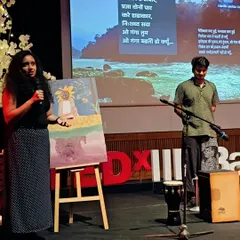 Explaining the concept behind the live painting at the TEDx event. The artwork, featuring a sunflower, was inspired by the theme of 'Roots & Wings' and the band's music about protecting our planet.