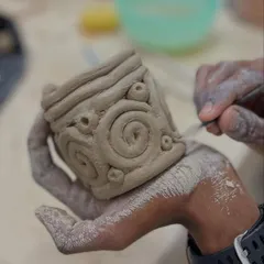 Hand-building allows for incredible detail. This student is carving intricate spiral patterns onto a cup they built by hand.