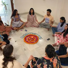 A powerful moment of connection as women hold hands in a circle, centered around a beautiful flower mandala. This symbolizes our unity and shared energy.