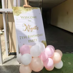 A simple yet elegant welcome sign for a 7th birthday party, personalized with the birthday girl's name and surrounded by pastel balloons.