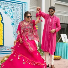 A fun and stylish couple's dance during their haldi ceremony, with both bride and groom wearing sunglasses and matching pink outfits.