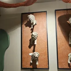 This unique wall art features a series of lion heads emerging from the surface, creating a bold and dramatic statement piece for an exterior or interior wall.