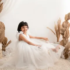 A beautiful solo portrait of a young girl in a flowing white dress. The boho-inspired setup with pampas grass creates a dreamy and ethereal atmosphere, perfect for celebrating her personality.