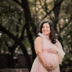 The radiant glow of motherhood captured in beautiful natural light. This mom-to-be smiles, surrounded by the soft greens of the park, creating a serene and joyful portrait.