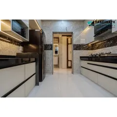 A parallel kitchen layout in Bhiwandi, designed for efficiency. The space features off-white cabinets with black profile handles, a dark granite countertop, and textured wall tiles for a modern, high-contrast look.