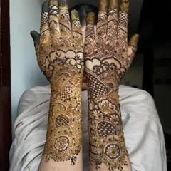 This is a classic Pakistani-style bridal design, characterized by bold outlines and very fine, intricate filler work. The contrast creates a dramatic and elegant effect, covering the arms completely.