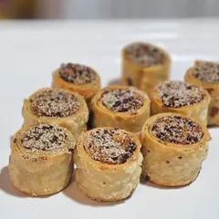 These are baked savory rolls, a modern take on a traditional snack. They are filled with a spiced mixture and offer a delightful crunch, perfect as a pass-around appetizer.