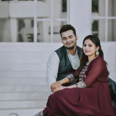 A classic and poised portrait of a couple on their special day. Seated on white steps, their pose is both elegant and intimate, showcasing their traditional attire and the beginning of their journey together.