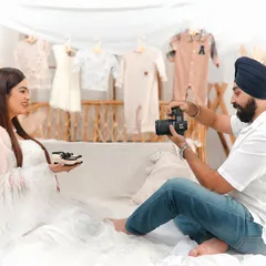 A behind the scenes style shot where the dad to be photographs his partner holding tiny baby shoes. It's a sweet way to capture the anticipation of their new arrival.