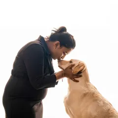 A tender kiss for a loyal friend. This high-key studio shot beautifully captures the love between an expectant mother and her dog, highlighting their special bond during this exciting time.