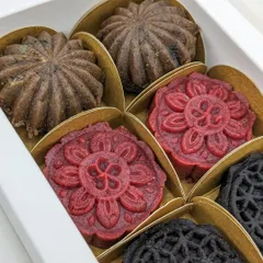 The complete assortment of our Christmas Cake Mithai, with intricate designs in festive colors of deep red, rich brown, and dark chocolate.