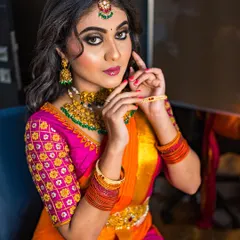 A close-up on a dramatic South Indian bridal look. The focus is the intense smokey eye with a touch of gold, paired with a bold lip and antique-finish temple jewelry.