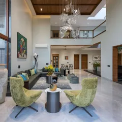 This double-height living room is designed for both grand entertaining and quiet relaxation. The soaring ceiling, overlooked by a second-floor gallery, creates an incredible sense of volume, while the custom glass chandelier acts as a piece of suspended art.