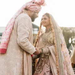 A beautiful moment between the bride and groom. Their coordinated pastel outfits, with his pink safa matching her lehenga, create a perfectly harmonious picture.