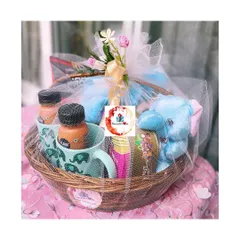 A charming gift basket for a family, featuring adorable elephant-themed mugs, a blue plush toy, and bottled drinks, all neatly wrapped in white tulle. It's a sweet gift for a family with young children.