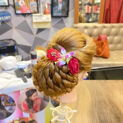 A student's beautifully finished bridal bun. Notice the clean lines, the intricate twisted base, and the perfectly placed floral accessories.