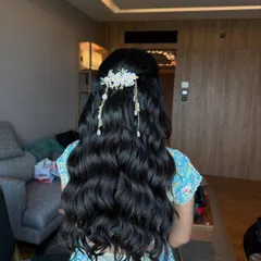 A stunning half-updo with long, flowing waves, decorated with a delicate floral hairpiece. This hairstyle is perfect for a modern bride who wants a romantic yet glamorous look.