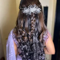 An elegant half-up, half-down hairstyle with a waterfall braid and a crystal hairpiece. This is a versatile look for engagements or receptions.